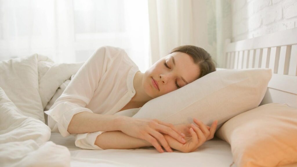 Woman peacefully sleeping in bed to illustrate better sleep tips