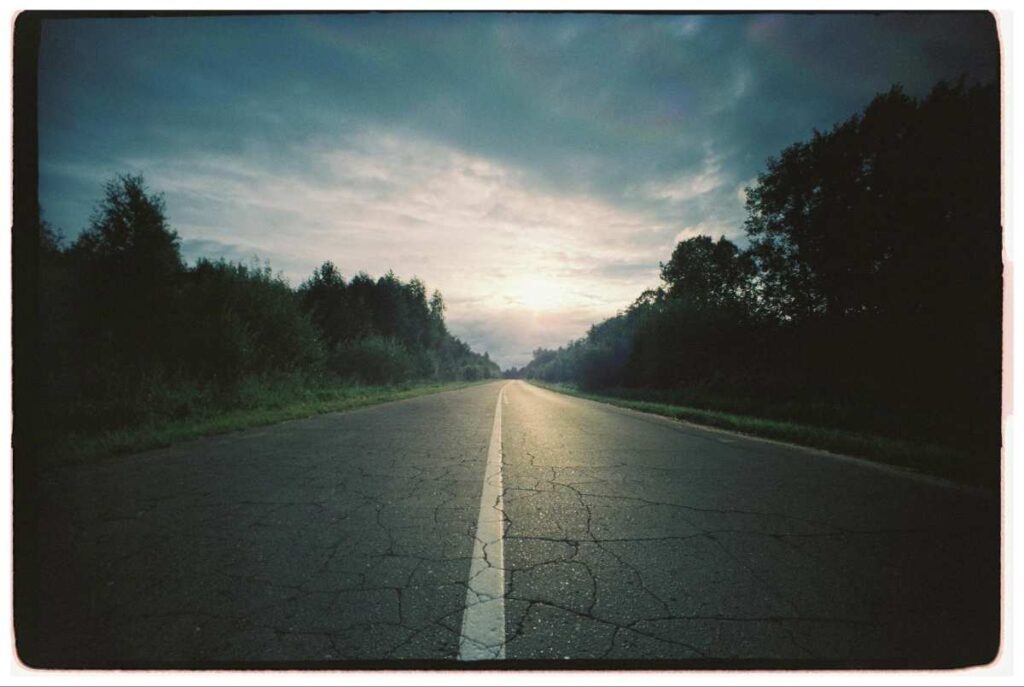 Lonely road under cloudy sky at sunrise symbolizing journey through suffering and hope