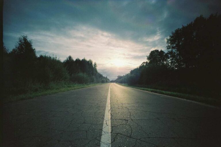 Lonely road under cloudy sky at sunrise symbolizing journey through suffering and hope