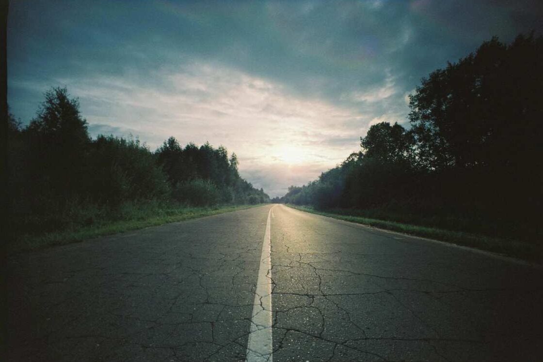 Lonely road under cloudy sky at sunrise symbolizing journey through suffering and hope