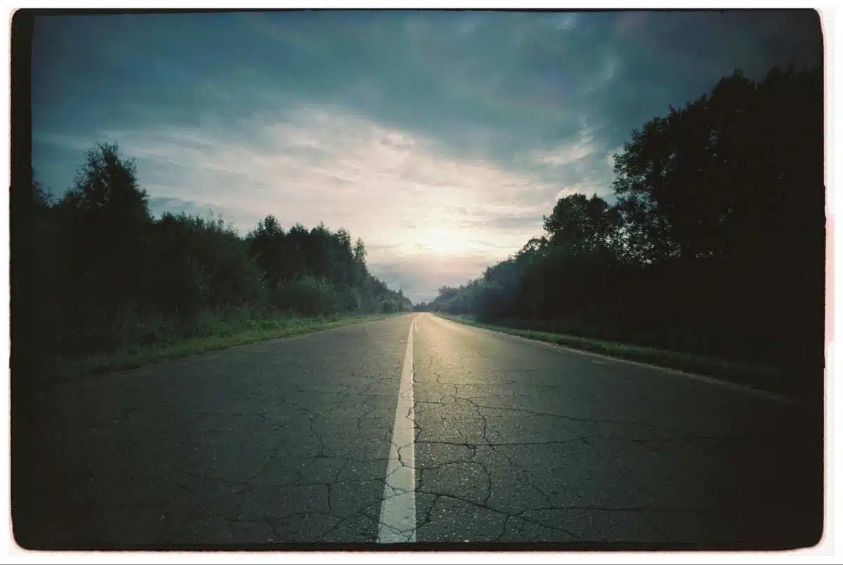 Lonely road under cloudy sky at sunrise symbolizing journey through suffering and hope
