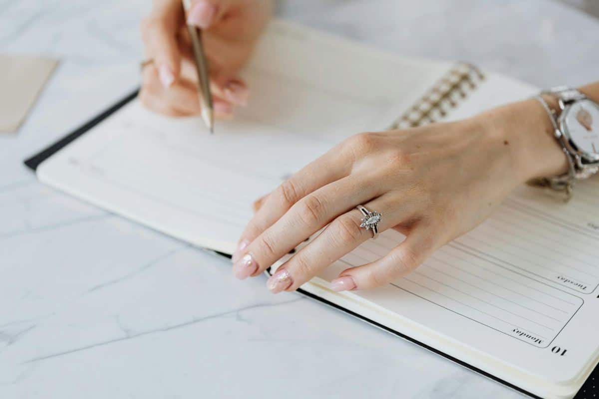 Close-up of a woman writing in a planner to establish daily routine