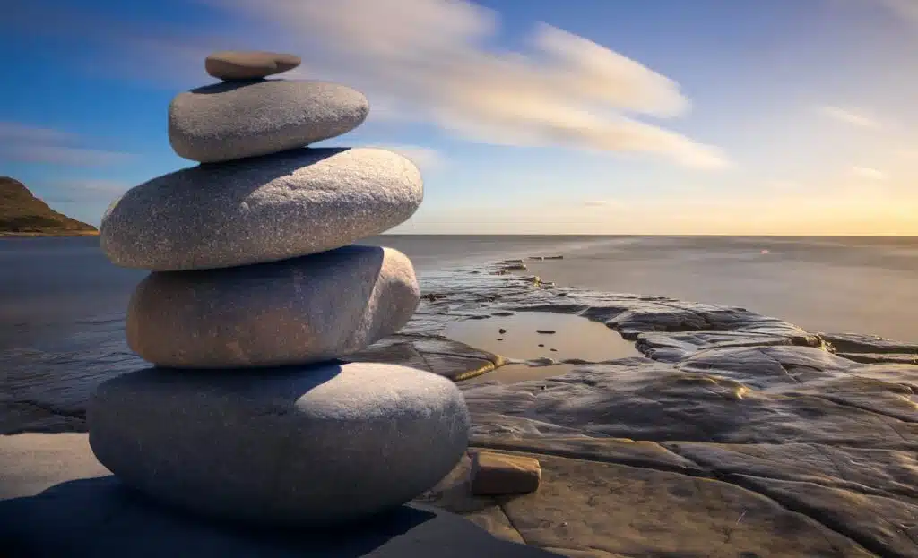 Stacked stones symbolizing balance and calm by the sea at sunset