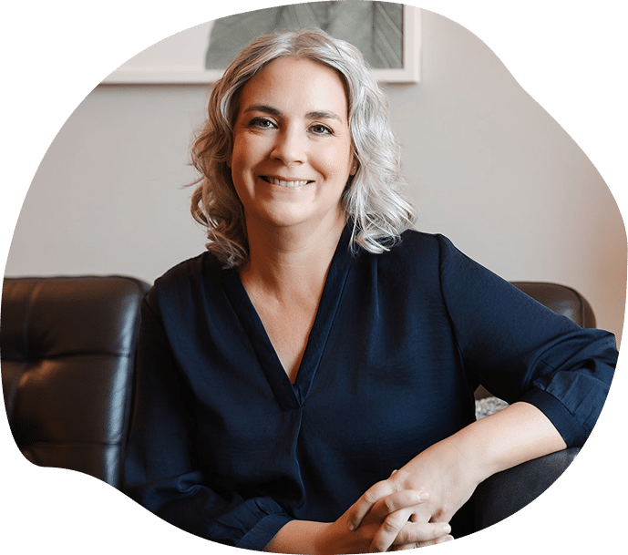 Gina Campbell sitting on a leather sofa holding a book