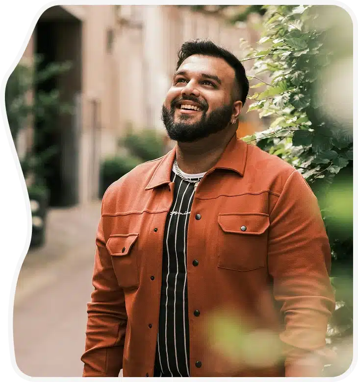Smiling man in an orange jacket looking up.