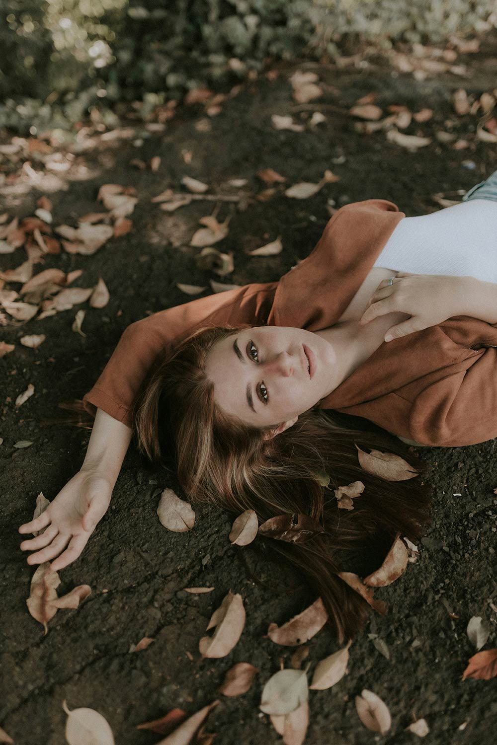 Woman lying on the ground among fallen leaves.